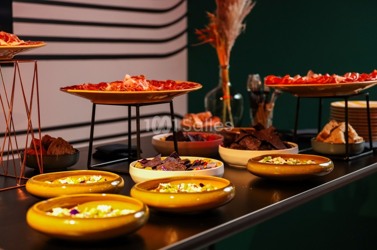 Table garnie de plats variés, incluant charcuteries, chips et sauces, dans un cadre moderne et chaleureux.