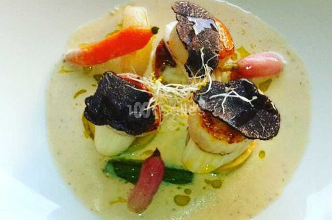 Noix de Saint-Jacques poêlées avec truffes noires, légumes colorés et sauce crémeuse, présentées dans une assiette blanche.
