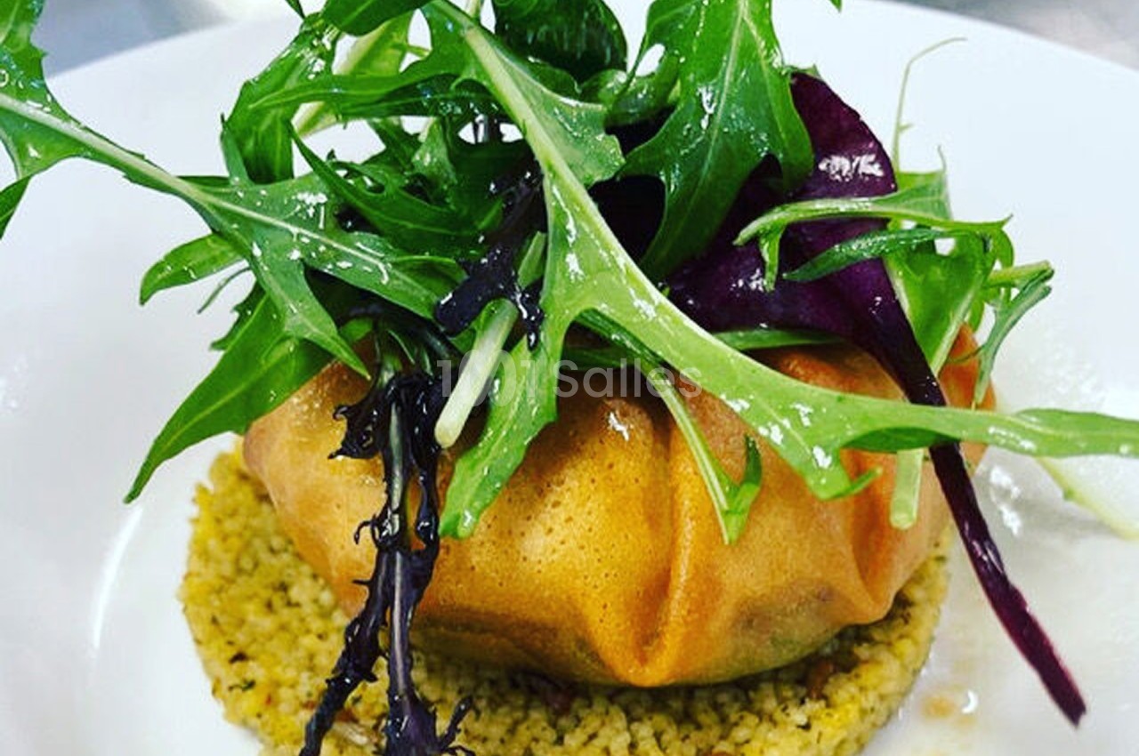 Plat composé d'une feuille croustillante garnie, posée sur du couscous et surmontée de jeunes pousses fraîches.
