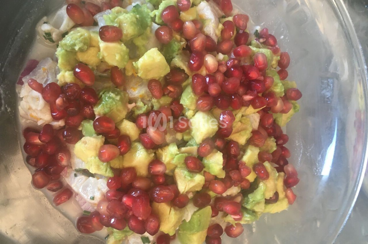 Salade composée d'avocat en dés, grains de grenade et autres ingrédients dans un bol transparent.