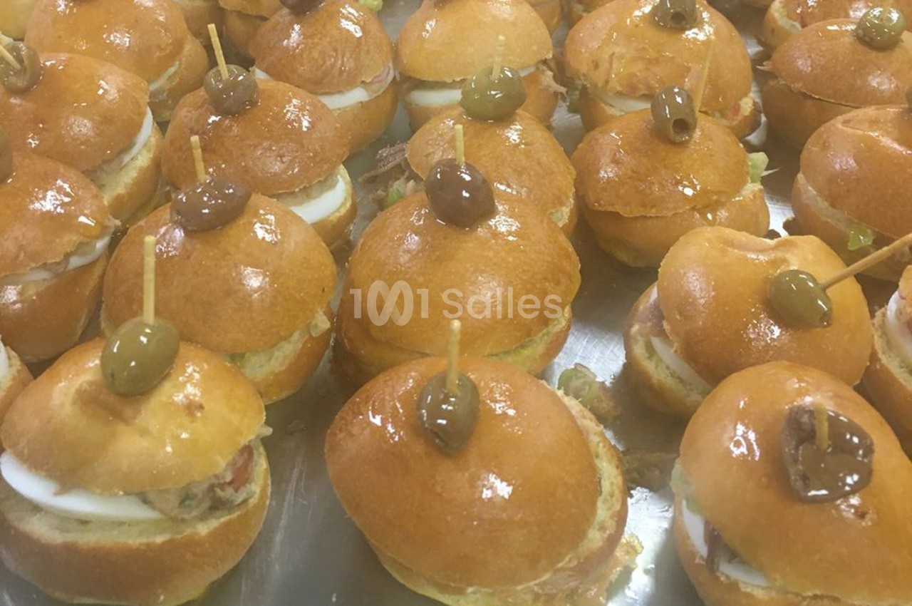Petits sandwichs ronds garnis de thon, œufs et olives vertes, présentés sur un plateau.