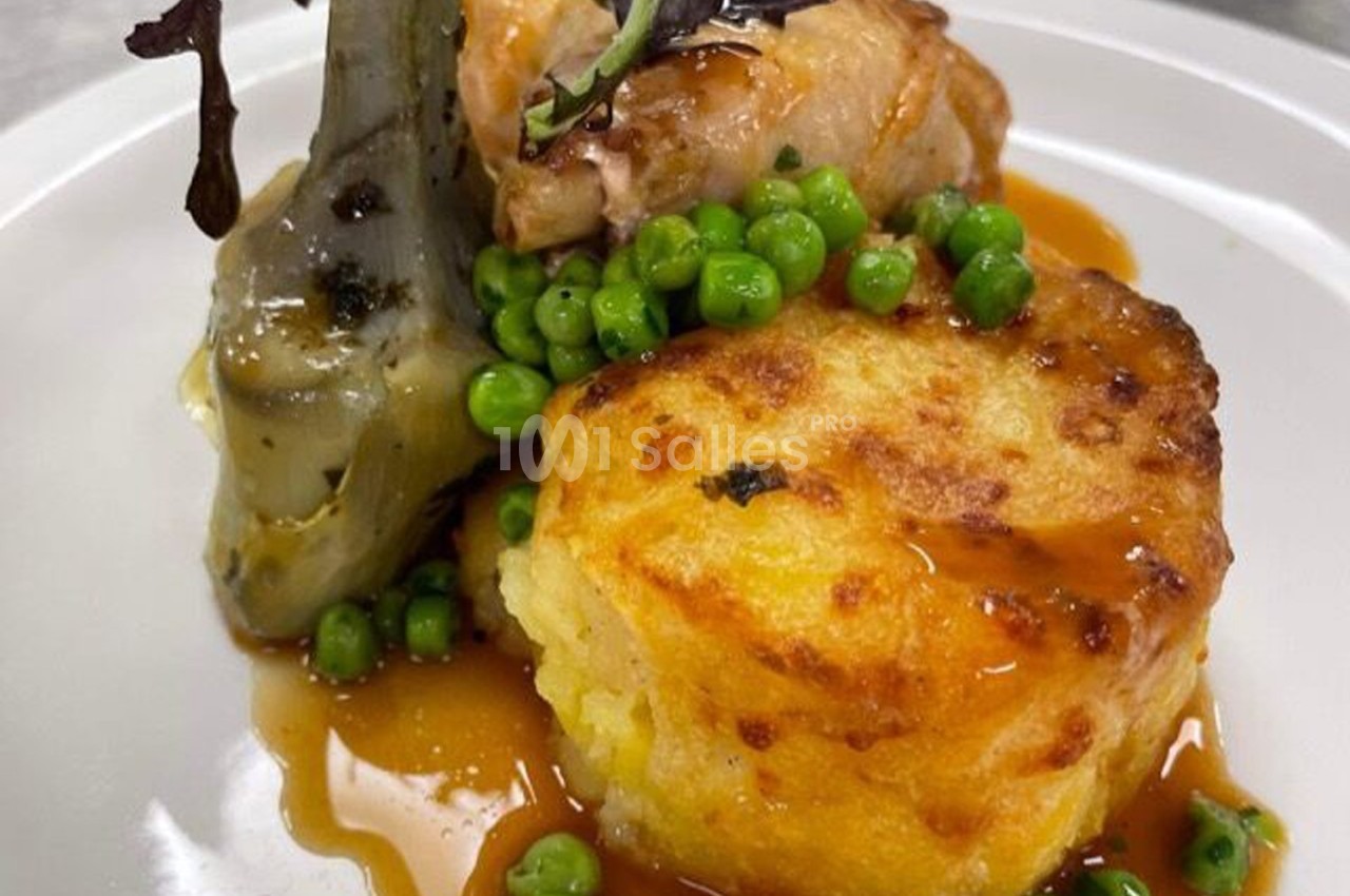 Assiette garnie d'un morceau de viande, d'un gratin doré, d'artichaut, de petits pois et d'une sauce brune.