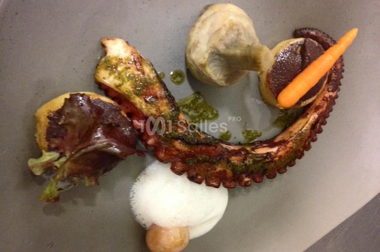 Assiette gastronomique avec tentacule de poulpe grillé, légumes, mousse blanche et sauce verte.