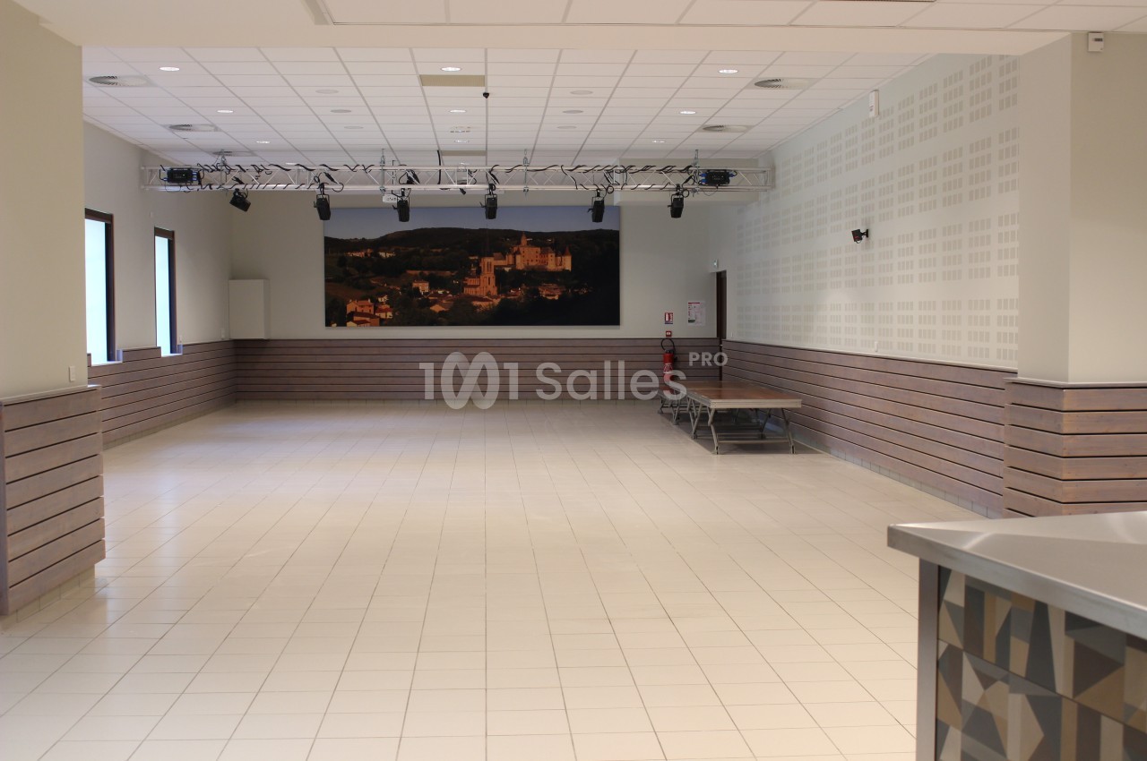Salle vide avec carrelage clair, murs blancs, éclairage au plafond et une grande photo d'un paysage accrochée au fond.