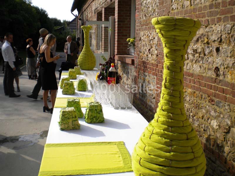 Table décorée avec des serviettes pliées en formes originales, disposée en extérieur près d'un mur en briques.