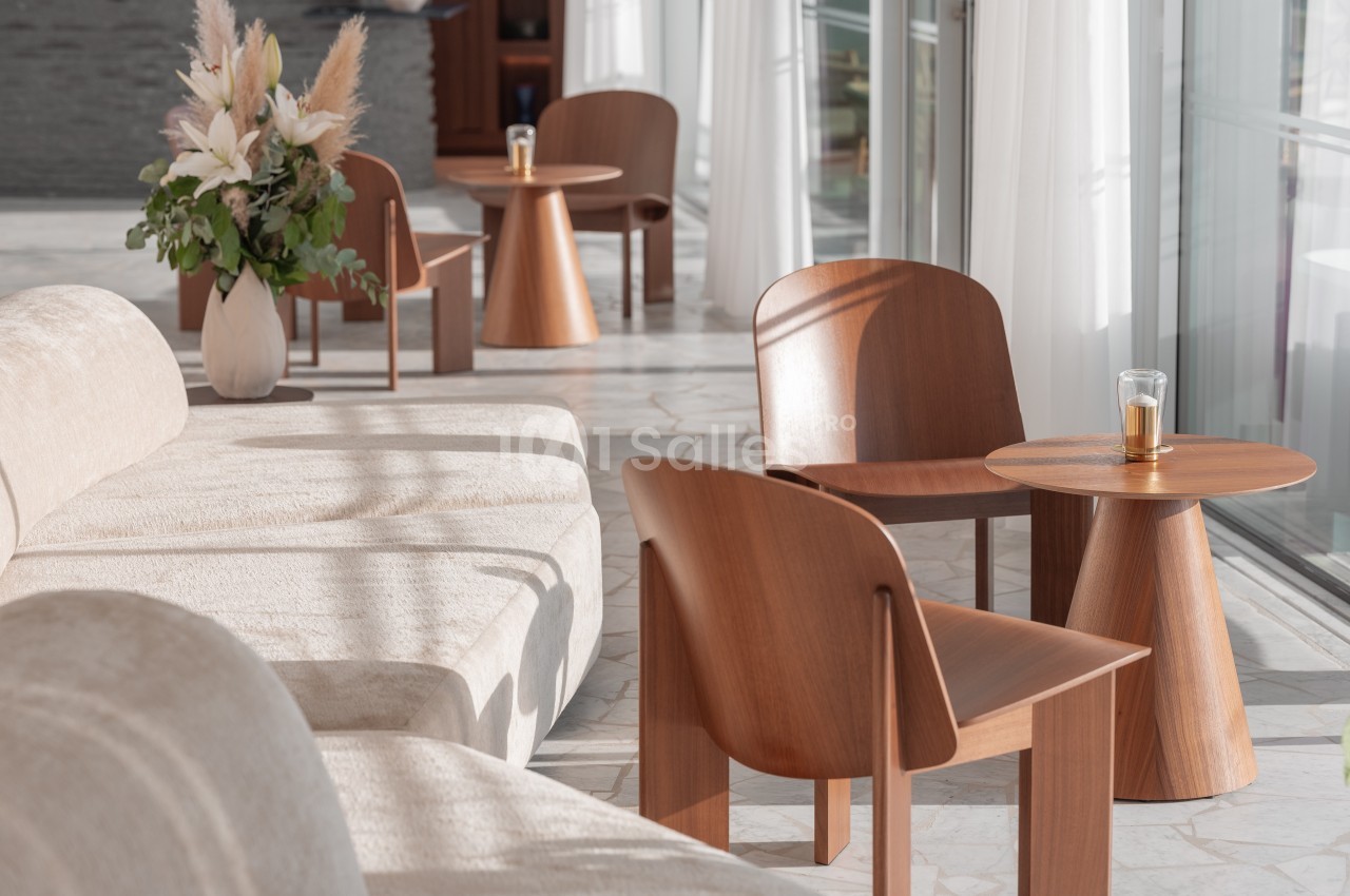 Espace lumineux avec fauteuils en bois, tables assorties et un bouquet de fleurs séchées sur une table.