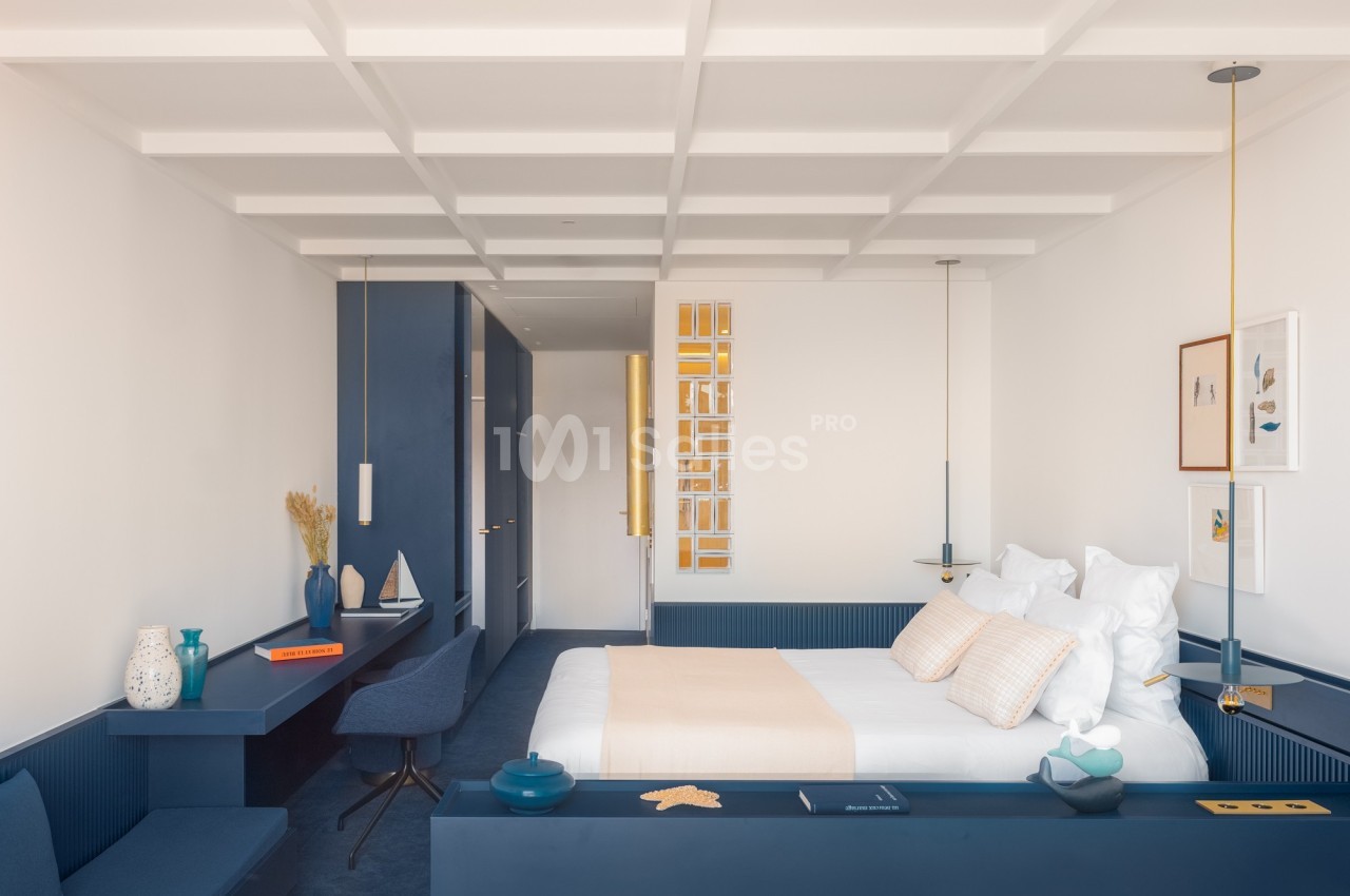 Chambre lumineuse avec lit double, mobilier bleu, décor minimaliste et touches décoratives modernes.