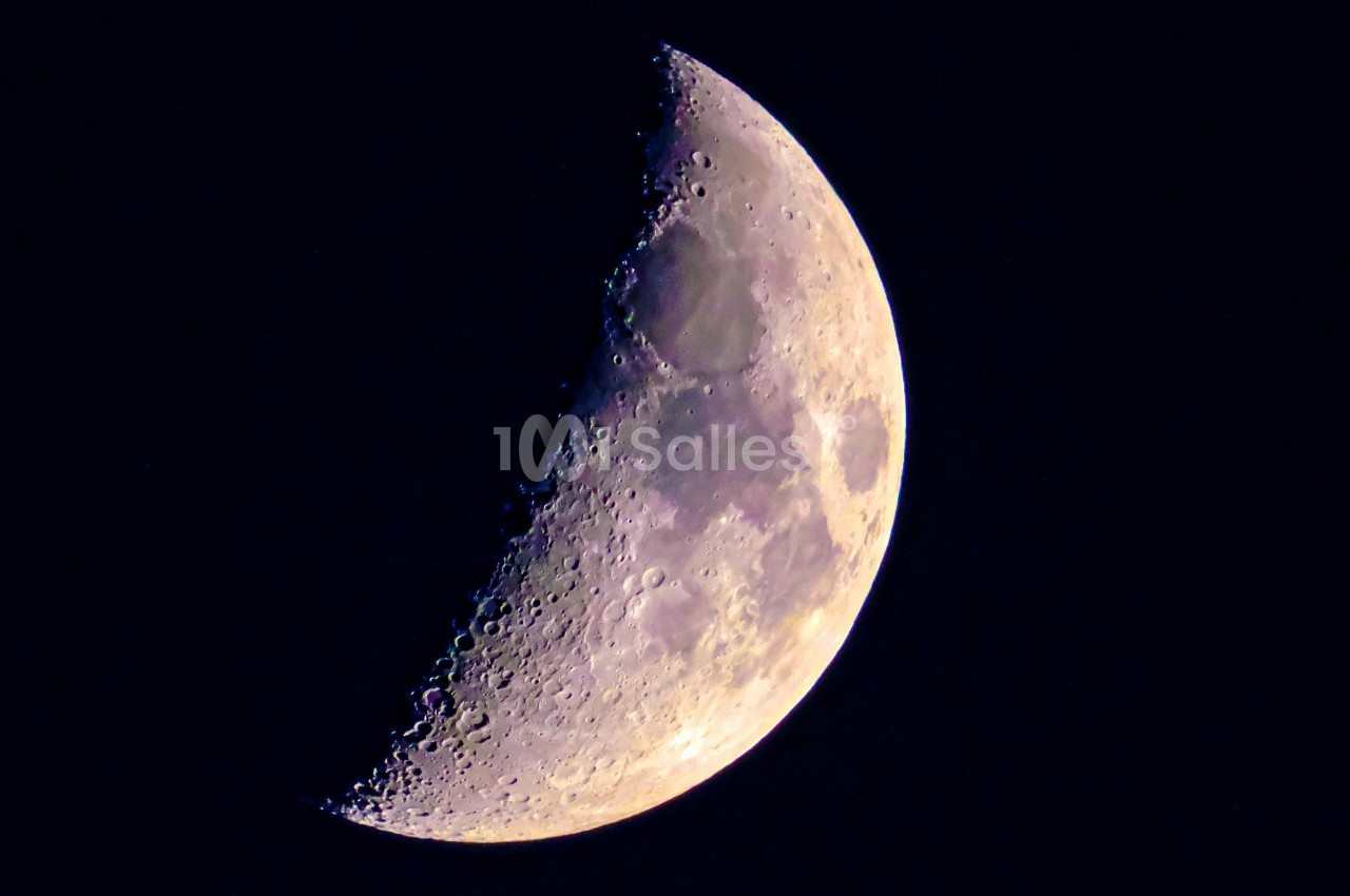 Croissant de lune illuminé partiellement, montrant des détails de sa surface dans un ciel nocturne sombre.