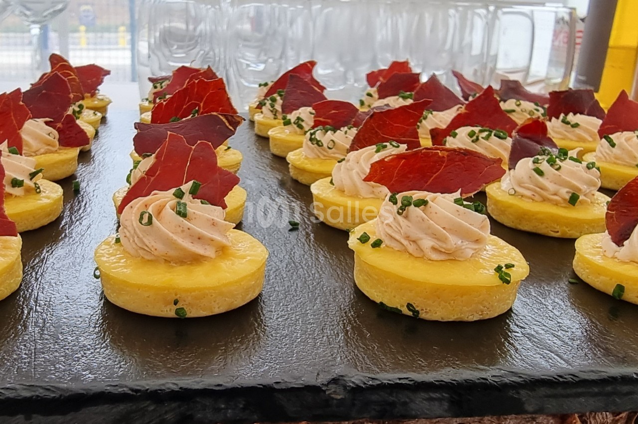 Assortiment de bouchées apéritives sur ardoise, composées de mousse salée, chips rouges et ciboulette.