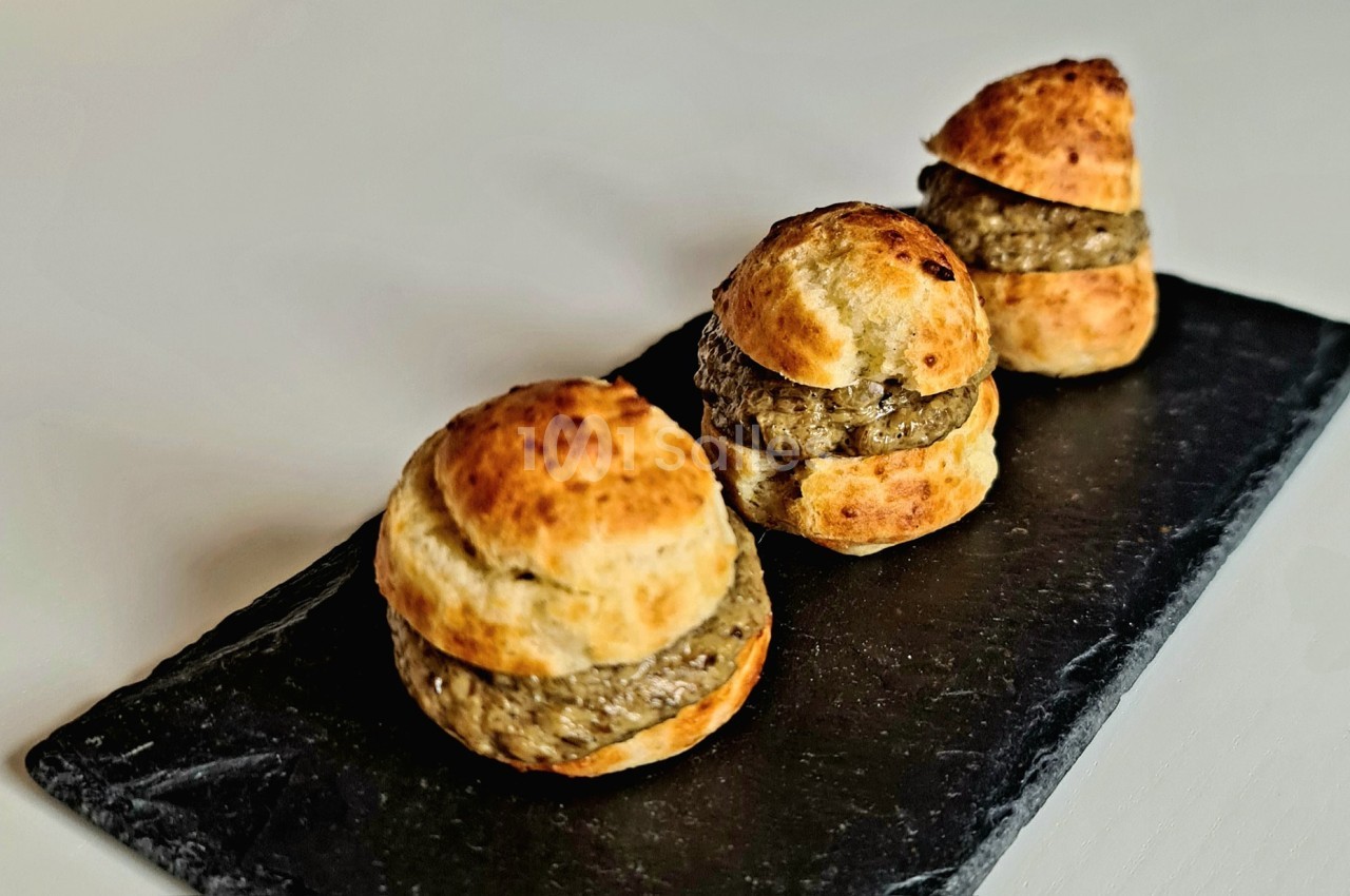 Petits choux garnis d'une mousse ou farce, disposés sur une ardoise noire.