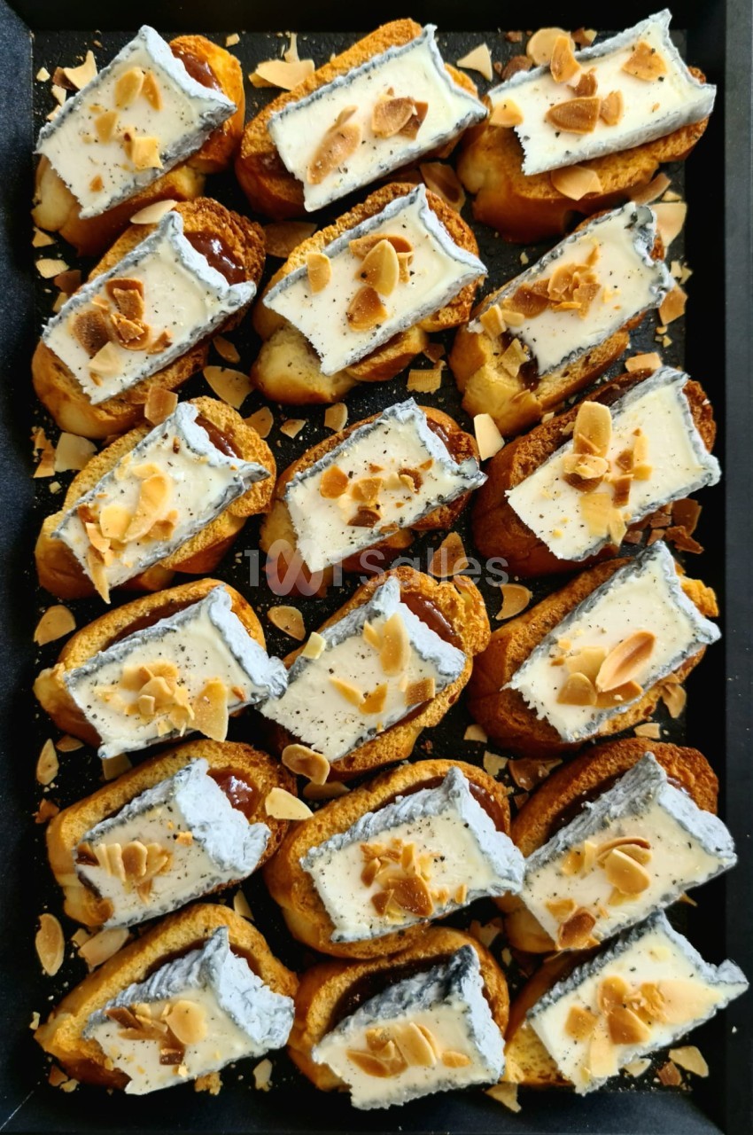 Plateau de pâtisseries garnies de crème blanche, nappées de chocolat et parsemées d'amandes effilées grillées.