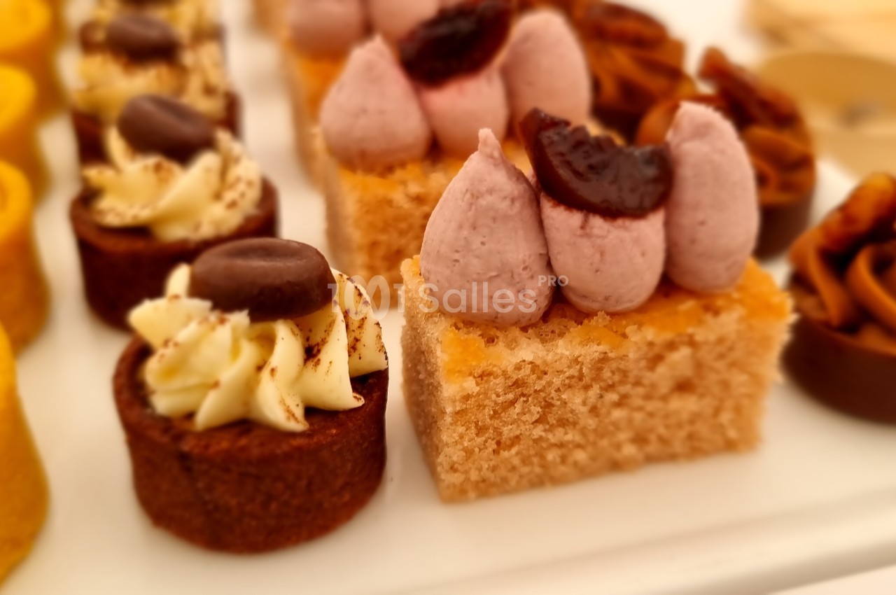 Assortiment de pâtisseries miniatures avec des garnitures variées, dont crème, fruits et chocolat, sur un plateau blanc.