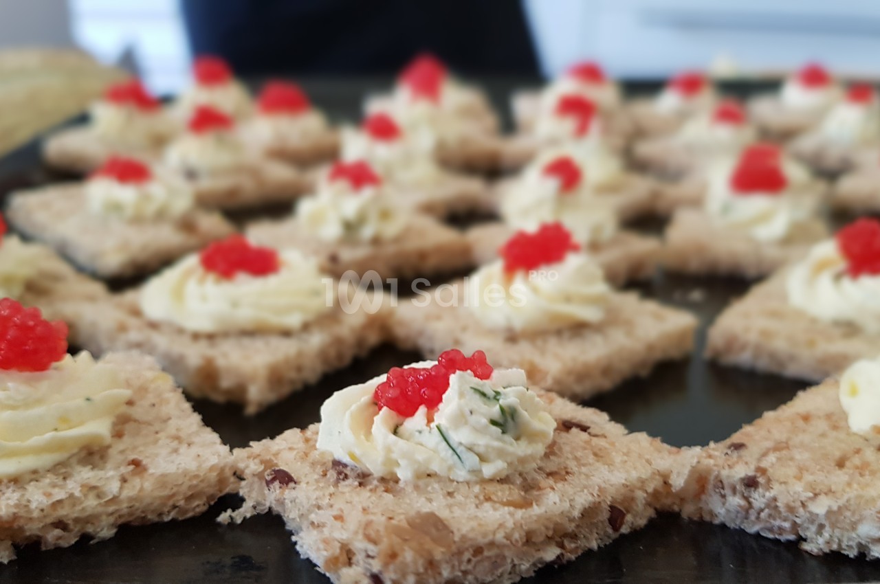 Toasts de pain complet garnis de crème à l'aneth et décorés de petites perles rouges.