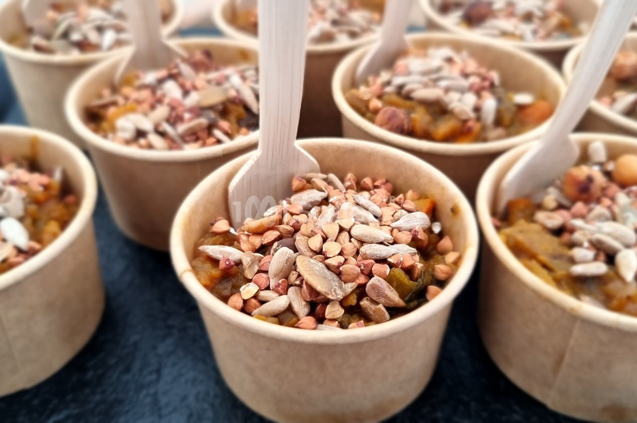 Petits pots en carton remplis de préparation garnie de graines et accompagnés de cuillères en bois.