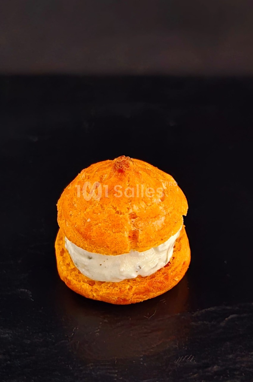 Chou garni de crème salée, posé sur une surface noire avec un fond sombre.
