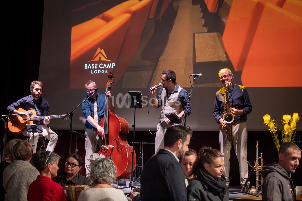 Un groupe de musiciens joue sur scène avec des instruments devant un public dans une salle de spectacle.