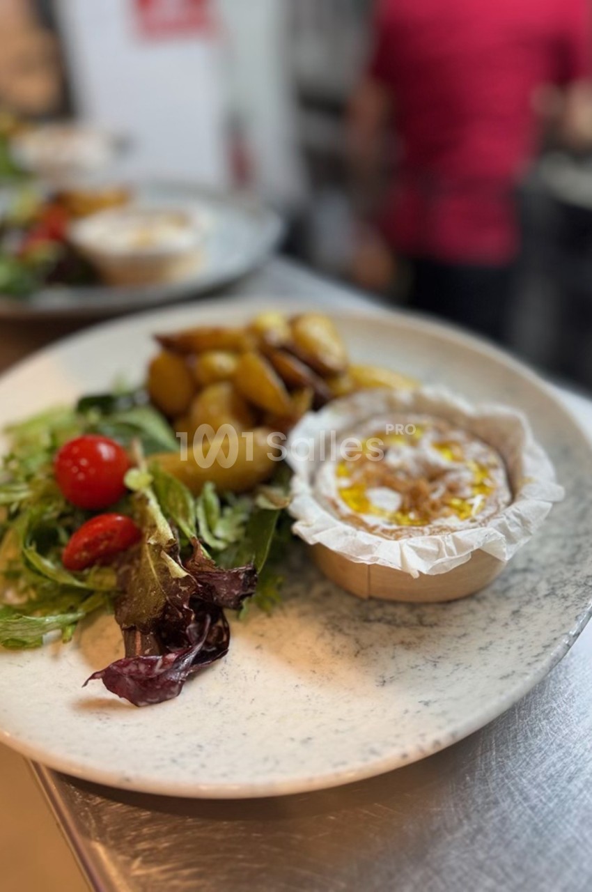 Assiette composée d'un camembert chaud, de pommes de terre rôties et d'une salade verte avec tomates cerises.