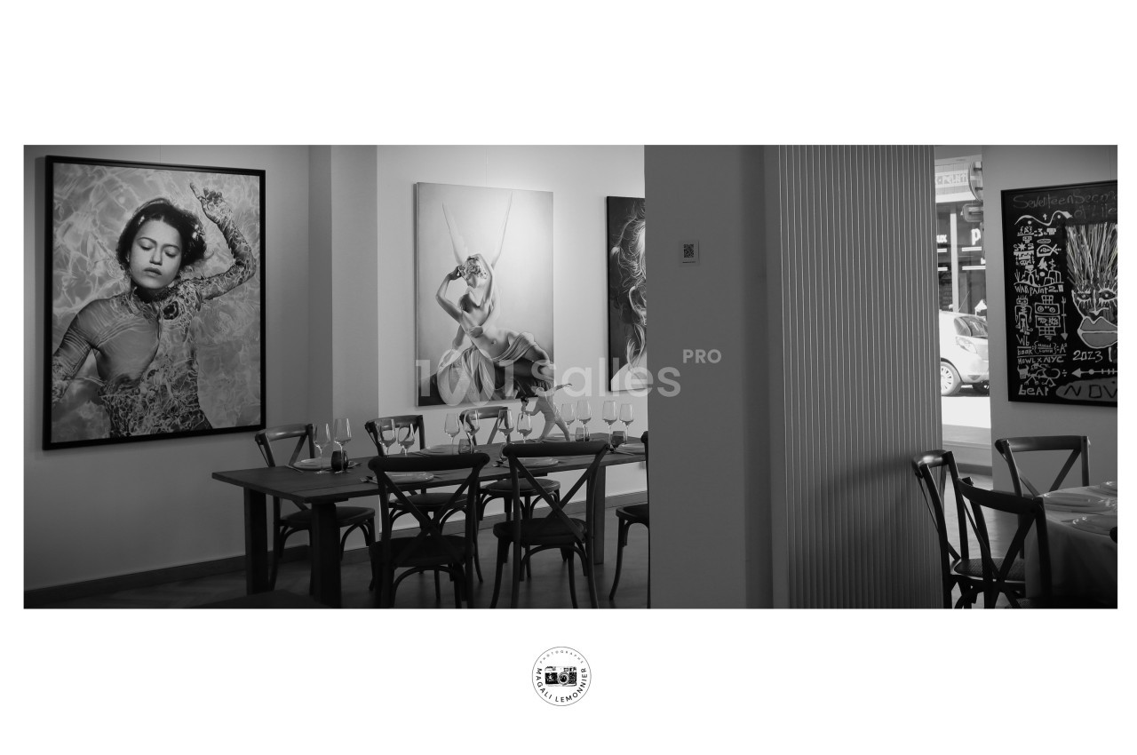 Salle de restaurant avec des tables dressées, décorée de grandes photographies en noir et blanc sur les murs.