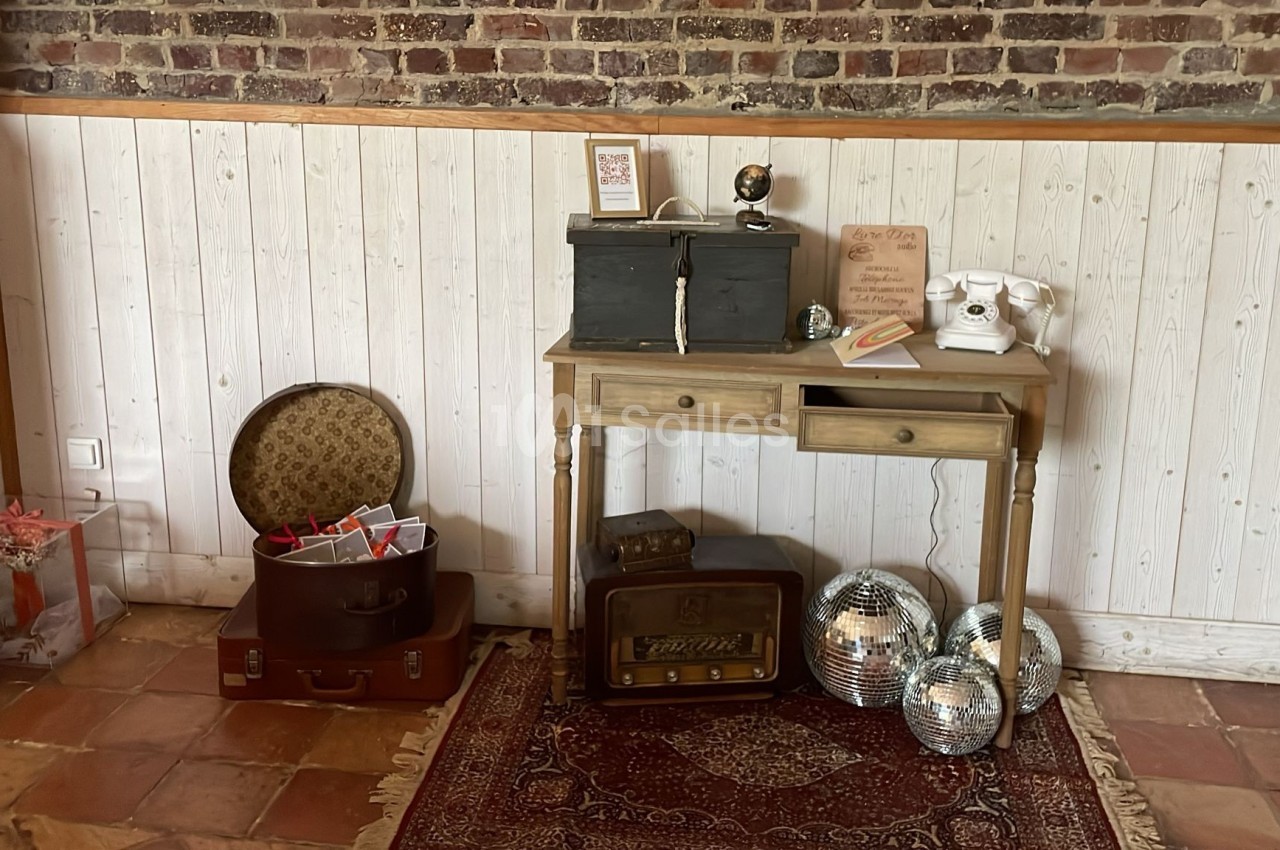 Un bureau en bois avec des objets vintage, entouré de valises, de boules à facettes et d'un mur en briques et lambris.