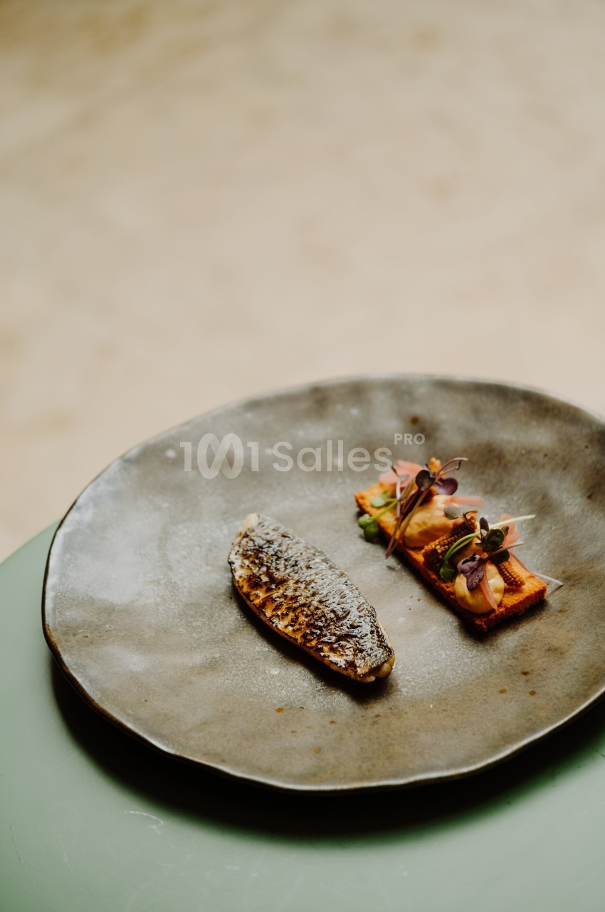 Filet de poisson grillé accompagné de légumes colorés et décoratifs, présenté sur une assiette en céramique.