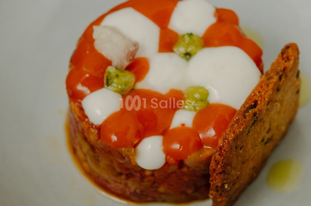 Tartare de légumes surmonté de sauces colorées, décoré de petits pois et accompagné d'un biscuit croustillant.
