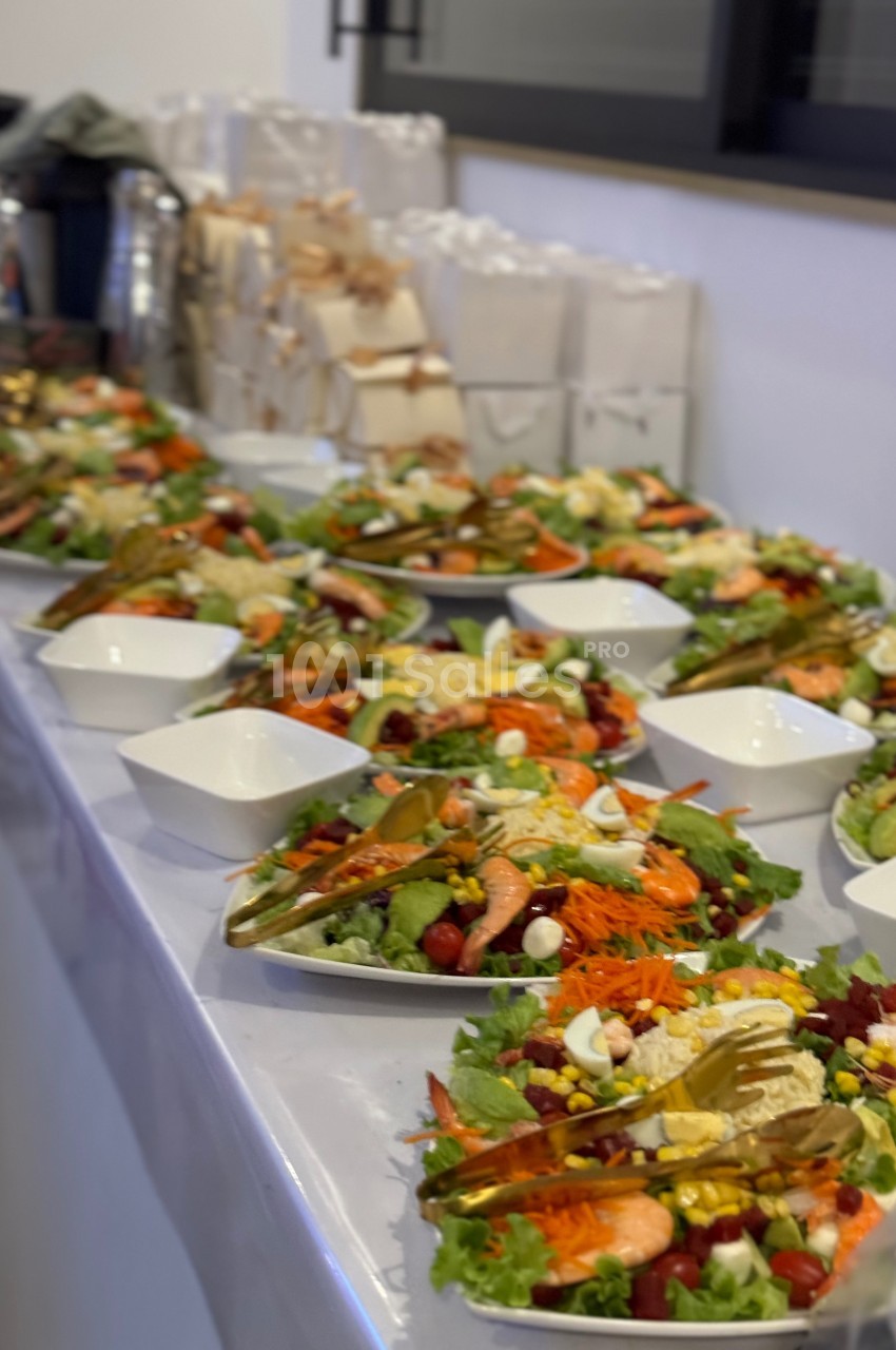 Assiettes de salades composées avec légumes, crevettes et œufs, alignées sur une table dans un cadre de réception.
