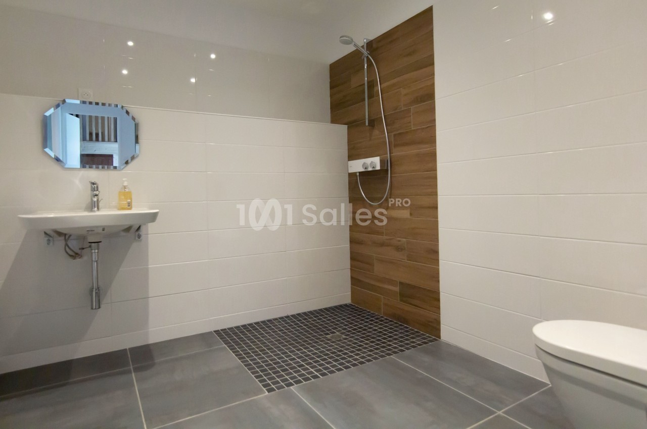 Salle de bain moderne avec douche à l'italienne, carrelage mural en bois, lavabo et miroir hexagonal.