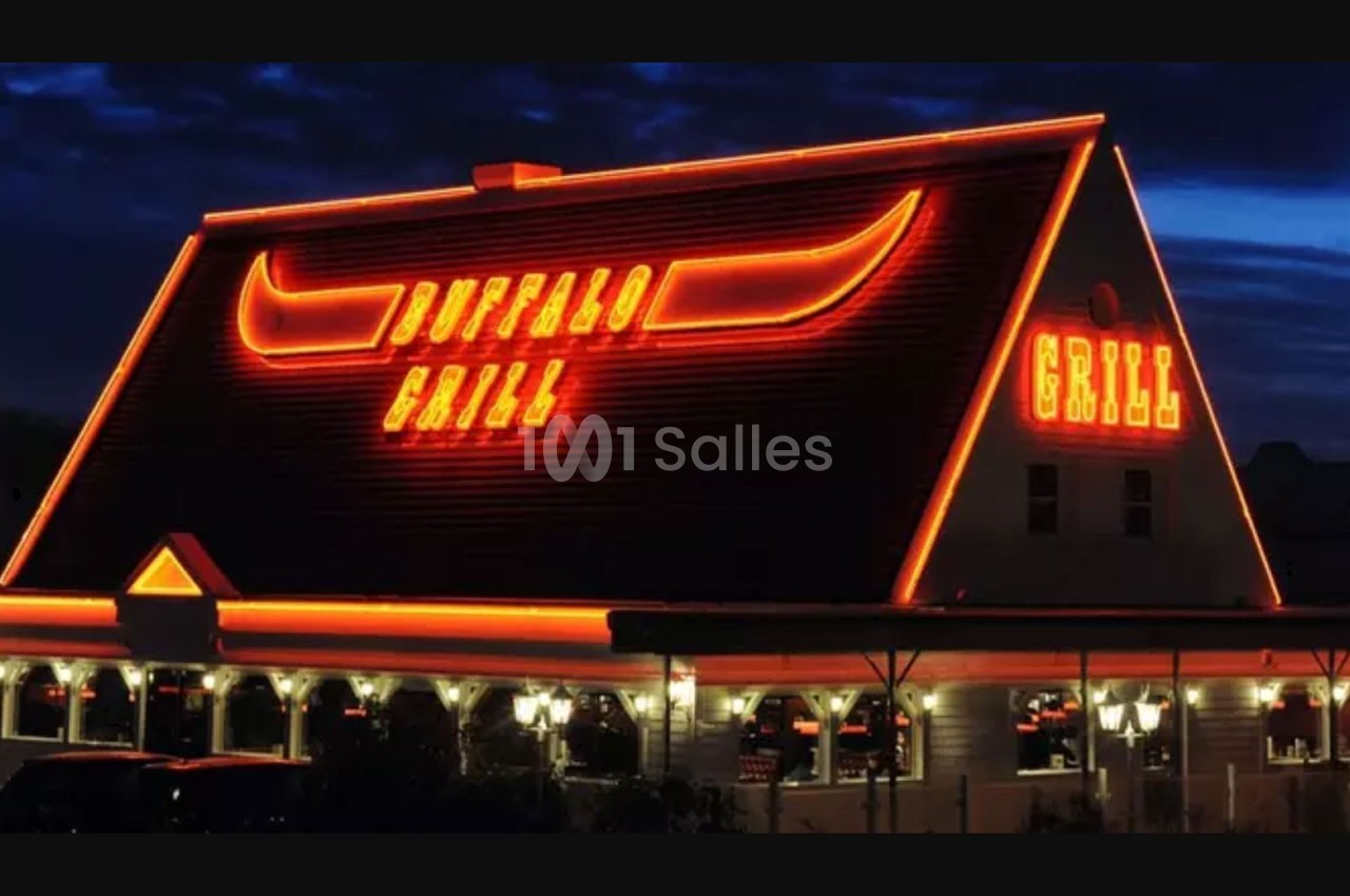 Façade d'un restaurant avec enseigne lumineuse rouge ’Buffalo Grill’ et toit en pente, éclairé de nuit.