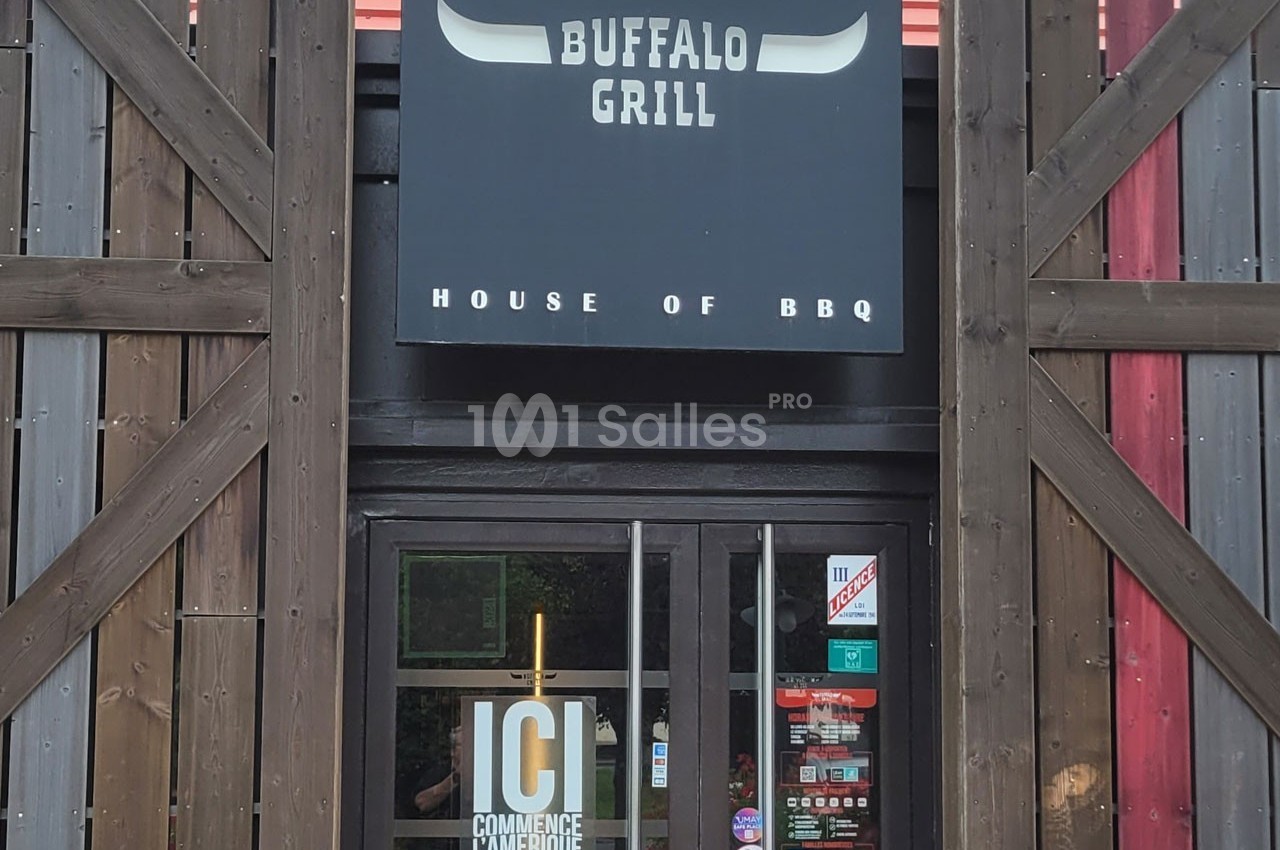 Entrée d'un restaurant avec une enseigne ’Buffalo Grill’ et une porte vitrée affichant des autocollants.