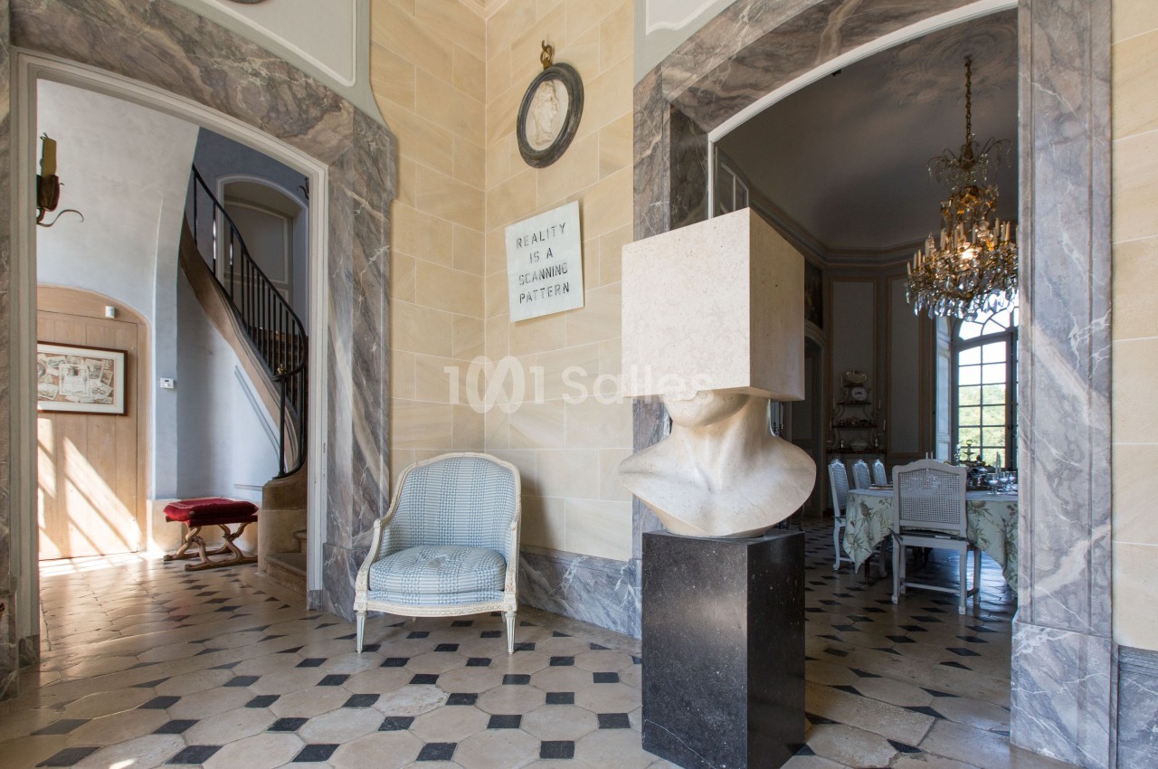 Intérieur élégant avec sol en damier, sculpture moderne, chaise en osier, escalier et salle à manger ornée d'un lustre.