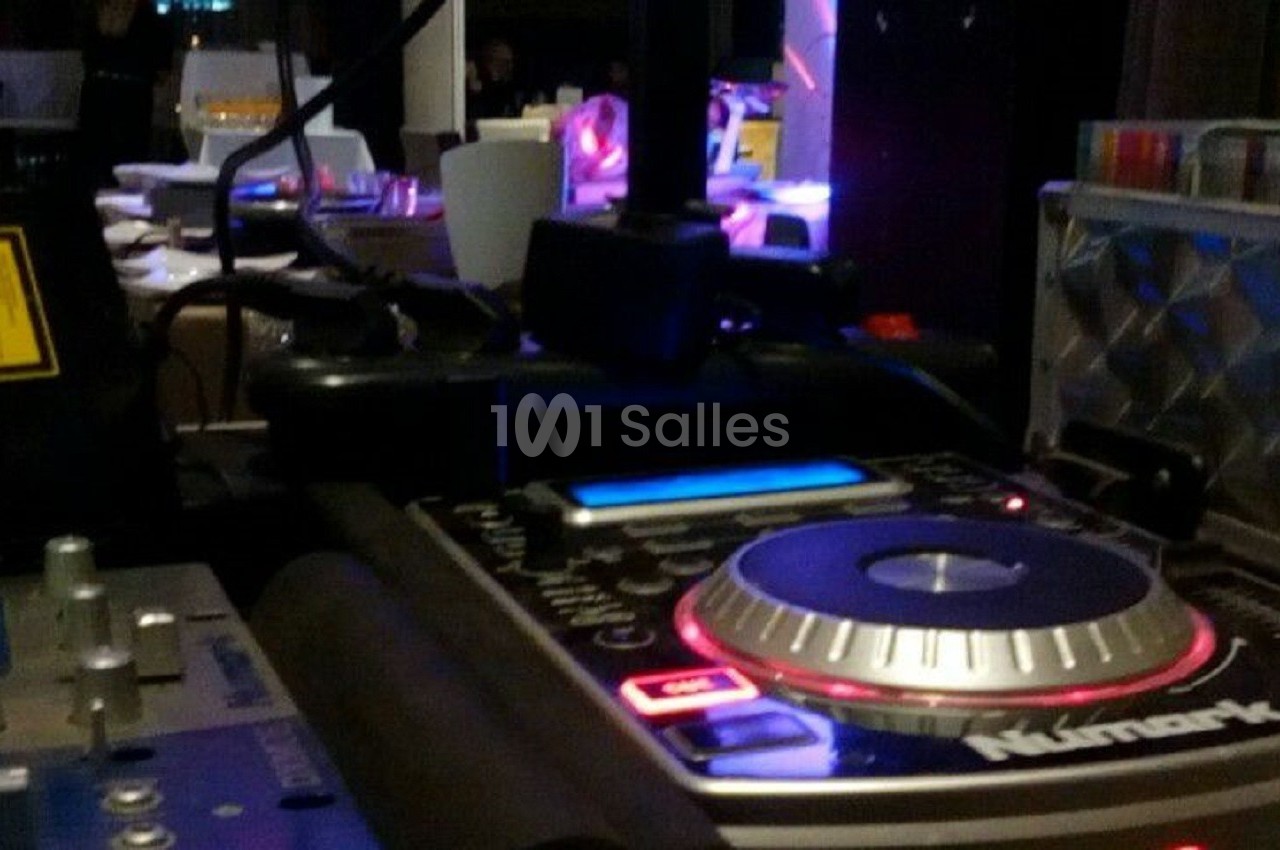 Console de mixage DJ avec éclairage coloré en arrière-plan dans un environnement intérieur.