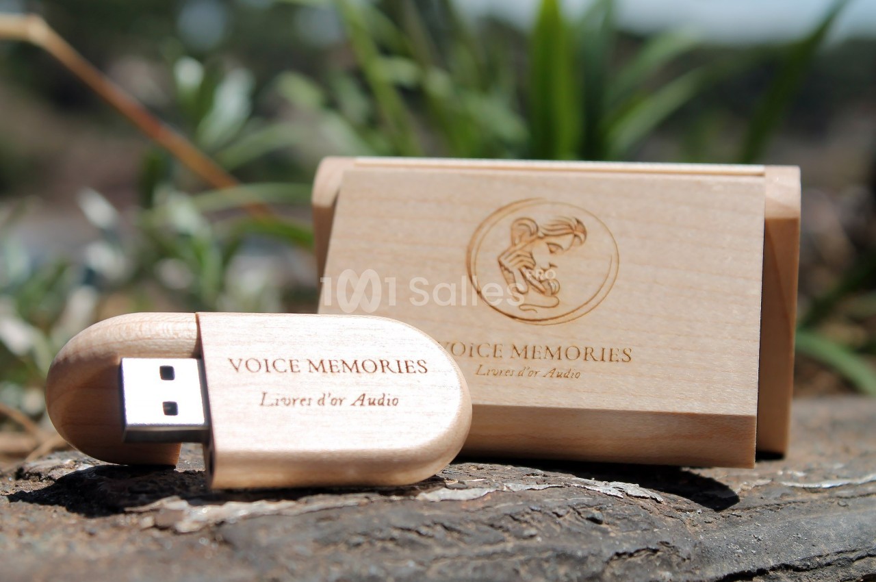 Clé USB en bois gravée ’Voice Memories’ avec son étui assorti, posée sur une surface naturelle.