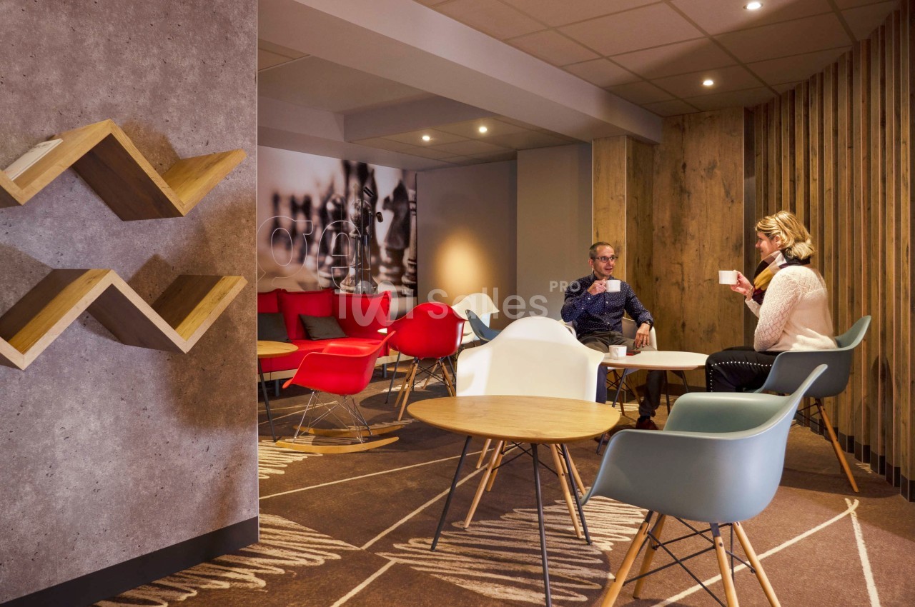 Deux personnes assises dans un espace lounge moderne avec des chaises colorées et une décoration en bois.
