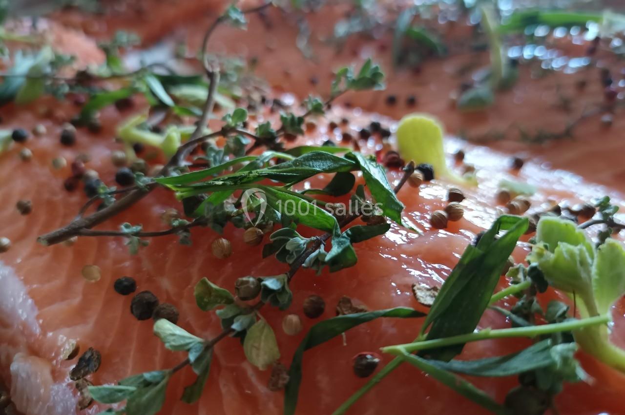 Filet de saumon cru garni de branches de thym, herbes fraîches et grains de poivre colorés.