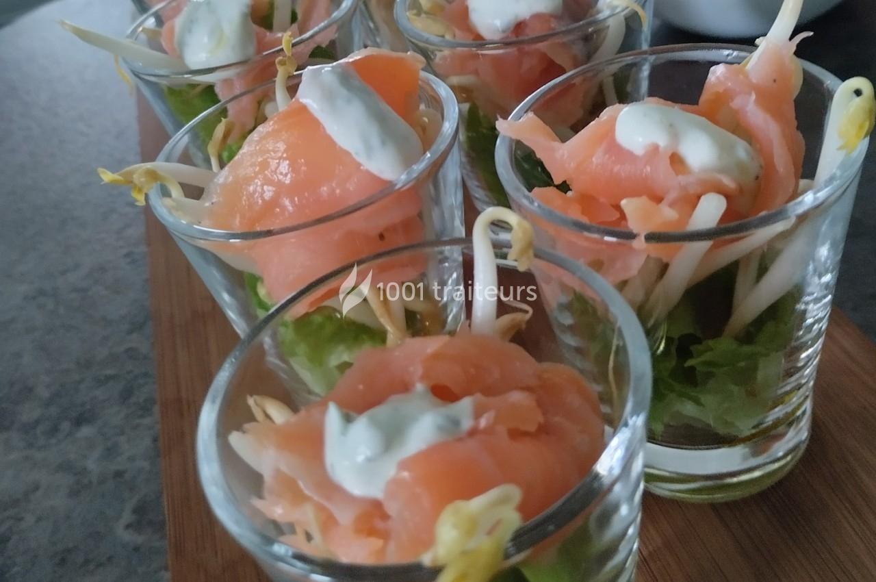 Verrines de saumon fumé avec pousses de soja, salade verte et sauce blanche, présentées sur un plateau en bois.