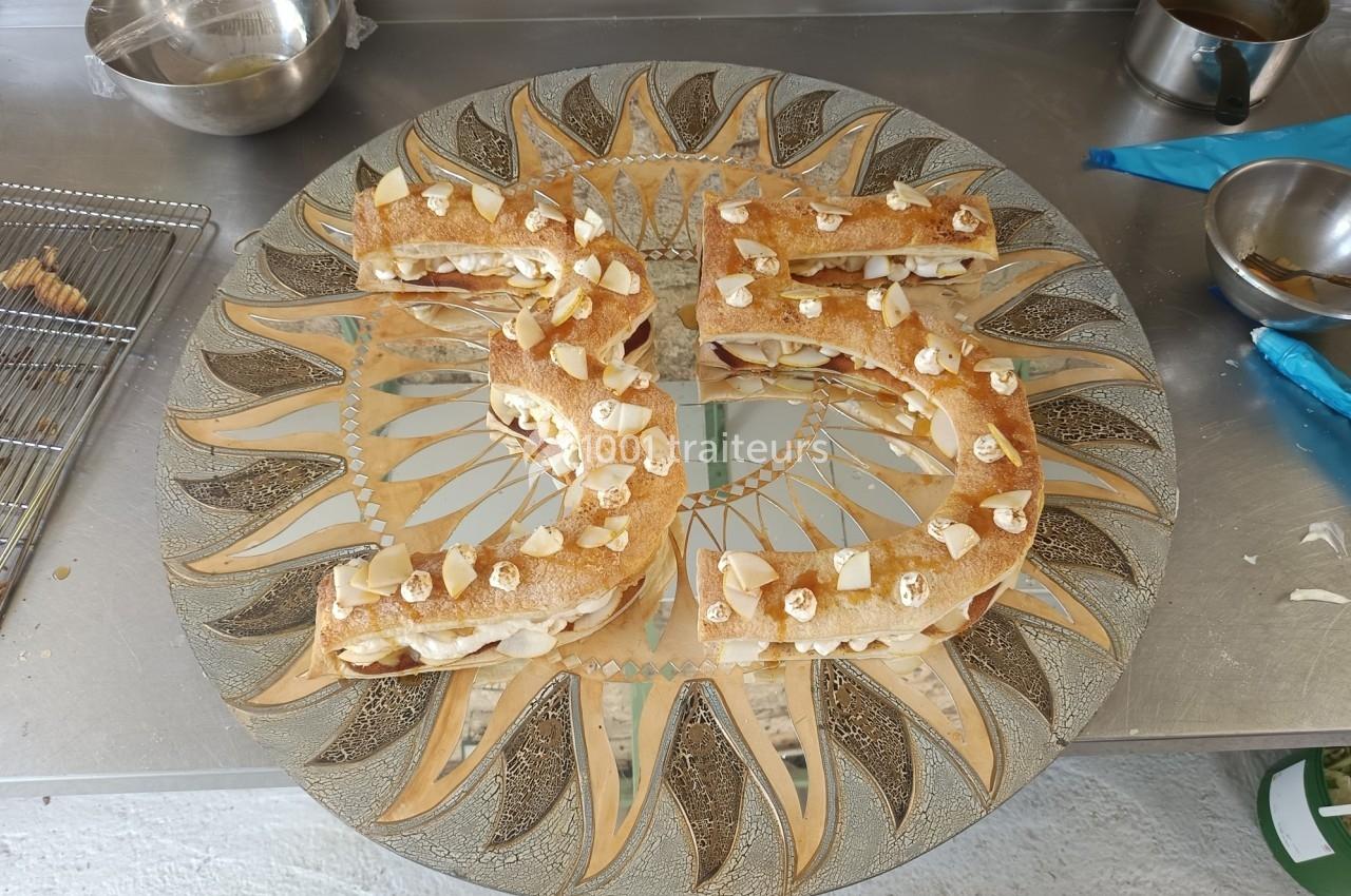 Pâtisserie en forme de chiffre 35, garnie de crème et décorée d'amandes sur un plateau orné de motifs dorés.