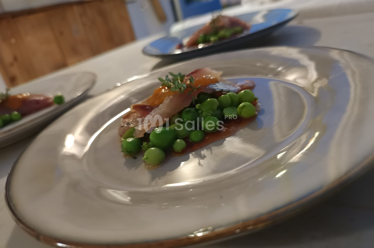 Assiette contenant des petits pois, une tranche de viande et une garniture, présentée sur une table.