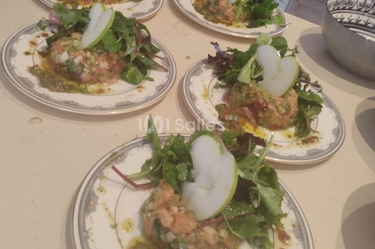 Assiettes de tartare de saumon garnies de jeunes pousses, tranches de pomme et sauce, servies sur une table.