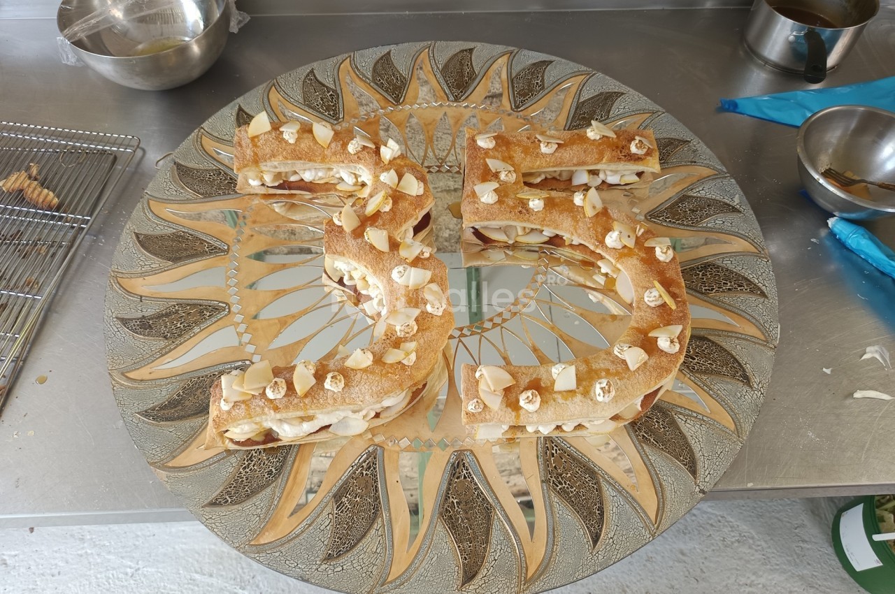 Pâtisserie en forme de chiffre 35, garnie de crème et décorée d'amandes sur un plateau orné de motifs dorés.
