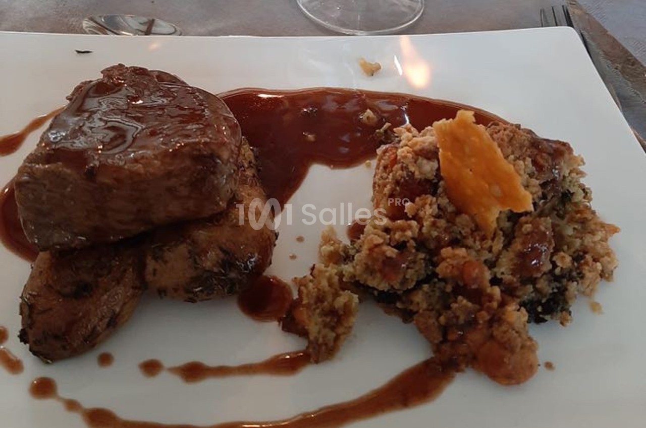 Assiette contenant un pavé de viande nappé de sauce, accompagné de pommes de terre et d'un crumble salé.