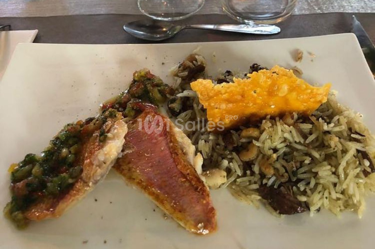 Assiette contenant du poisson grillé avec une sauce, du riz aux champignons et une tuile de fromage croustillante.