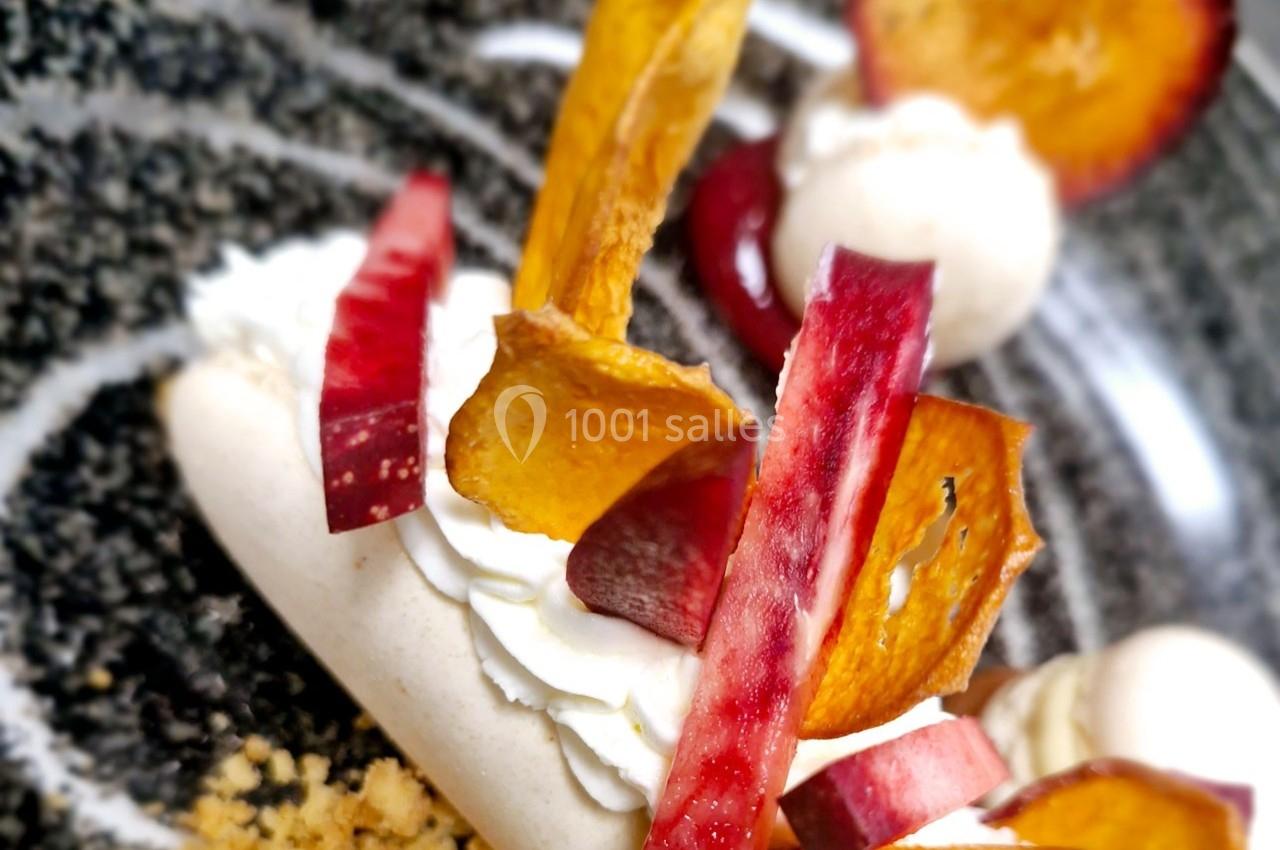 Dessert composé de meringue, crème fouettée, chips de fruits et morceaux de fruits rouges sur une assiette noire.