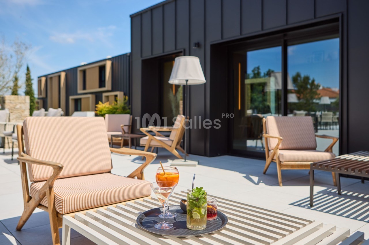 Terrasse moderne avec fauteuils en bois, table basse et plateau contenant des boissons et un dessert.