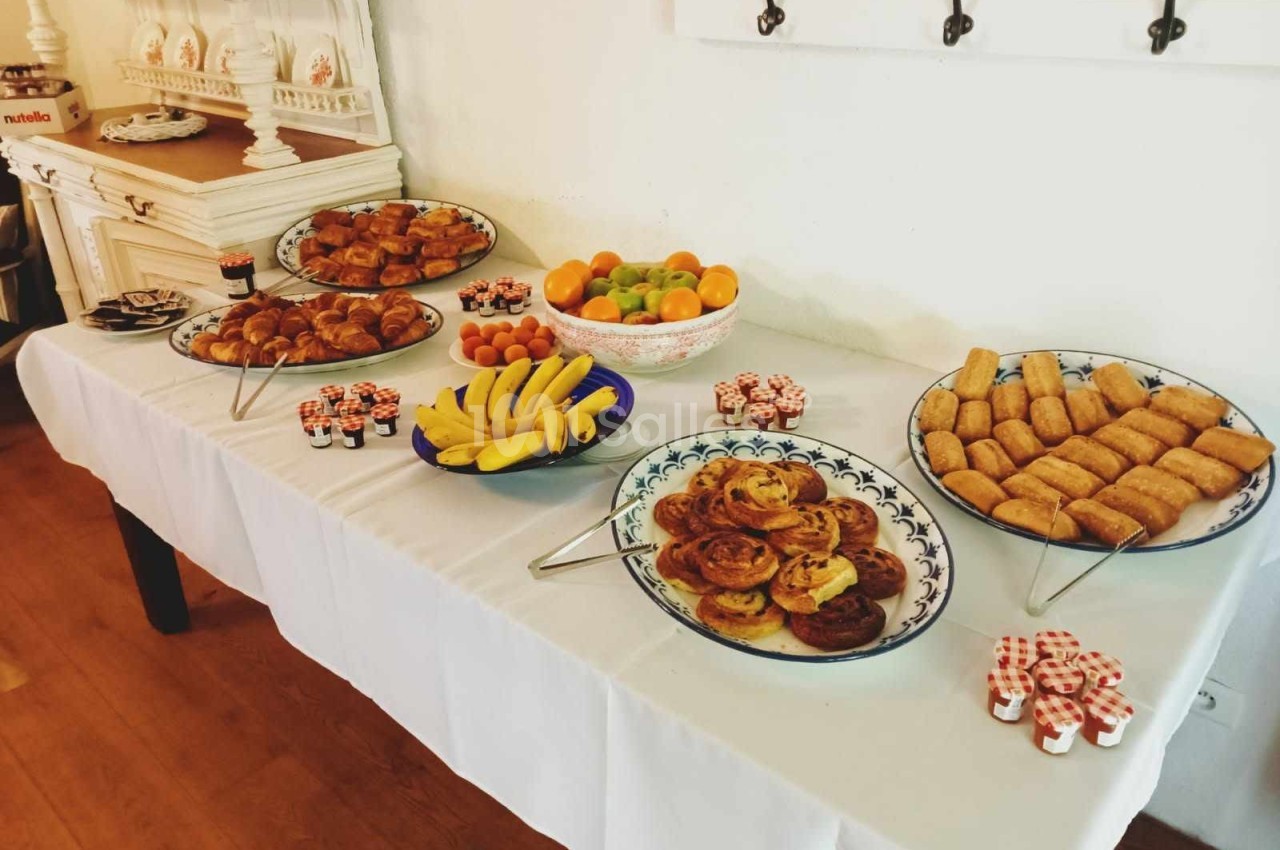 Buffet de petit-déjeuner avec viennoiseries, fruits, confitures en portions individuelles et autres mets sur une table…