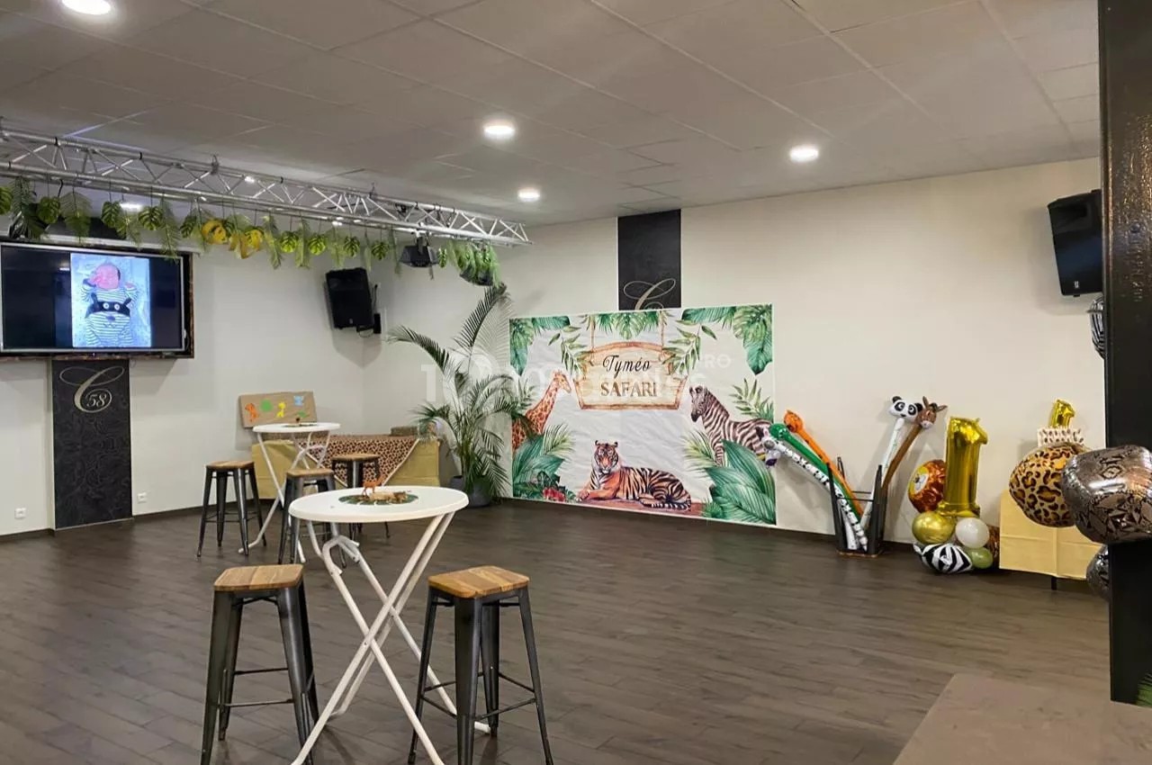 Salle décorée sur le thème safari avec plantes, animaux gonflables, table haute et scène équipée d'un écran.