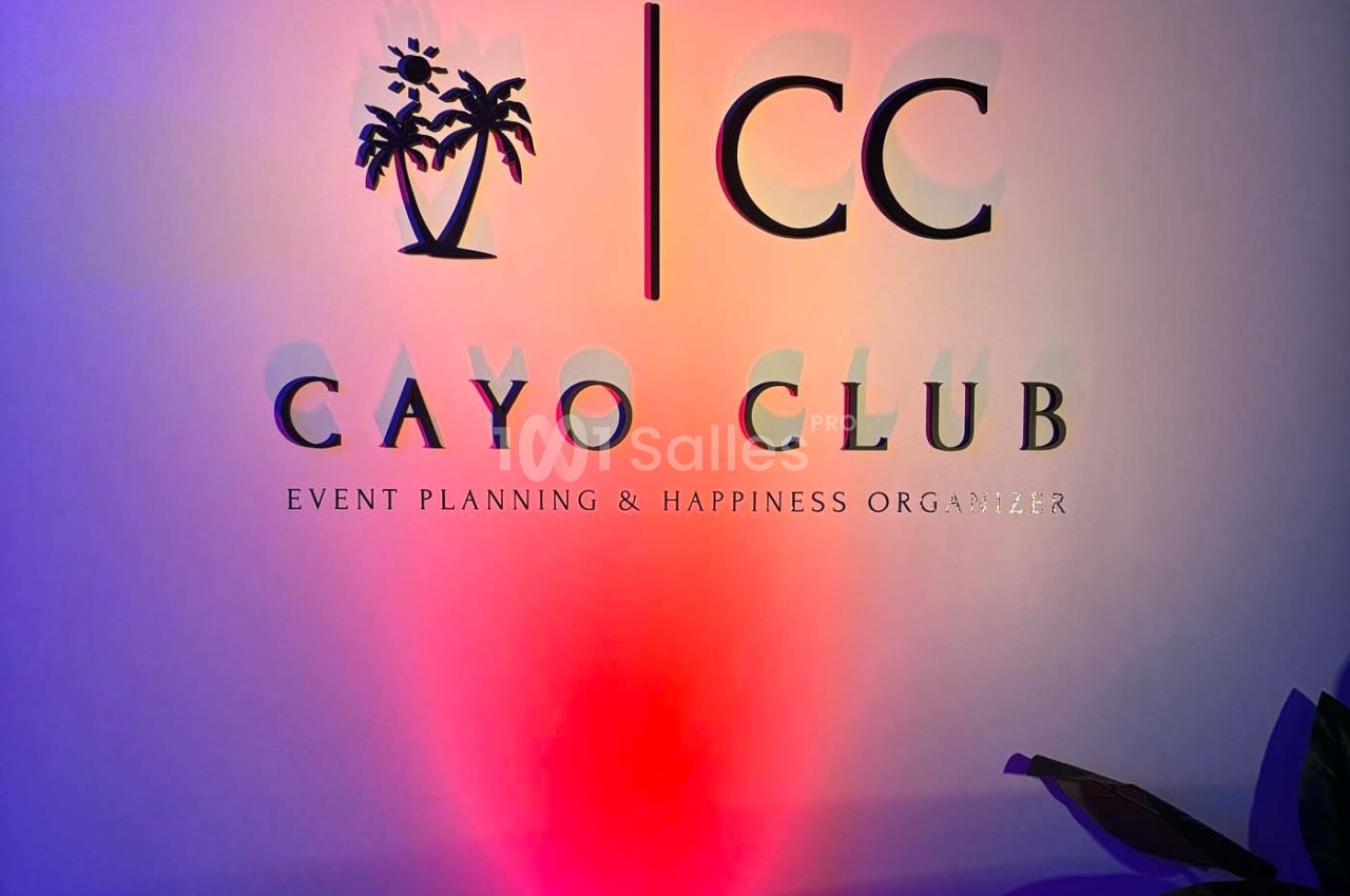 Mur avec le logo ’Cayo Club’, des palmiers stylisés et le slogan ’Event Planning & Happiness Organizer’.