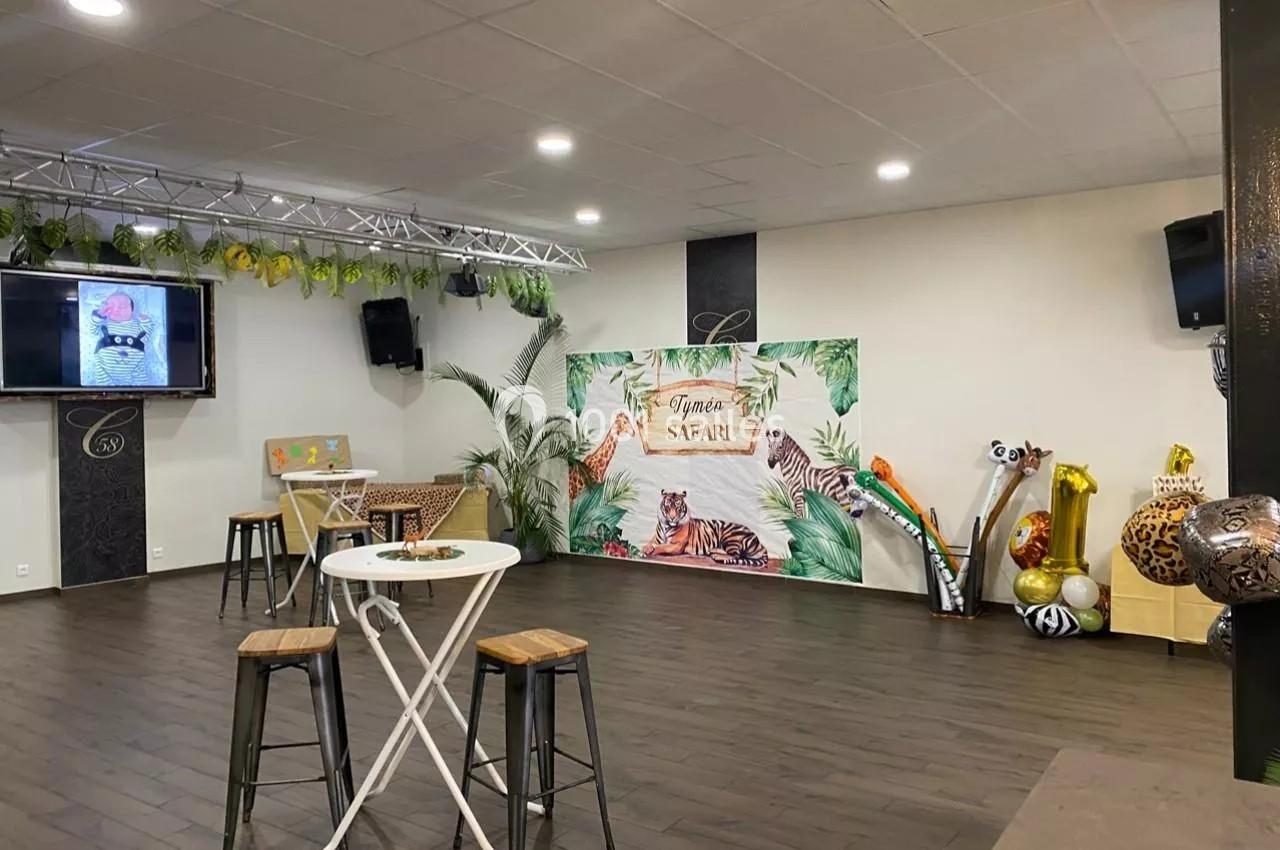 Salle décorée sur le thème safari avec des plantes, des ballons animaux et une table haute au premier plan.