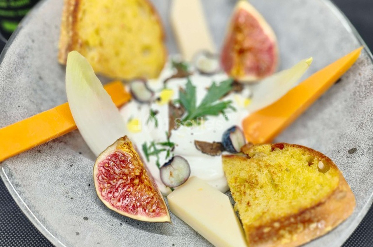 Assiette composée de burrata, figues fraîches, endives, fromage, myrtilles et tranches de pain grillé.