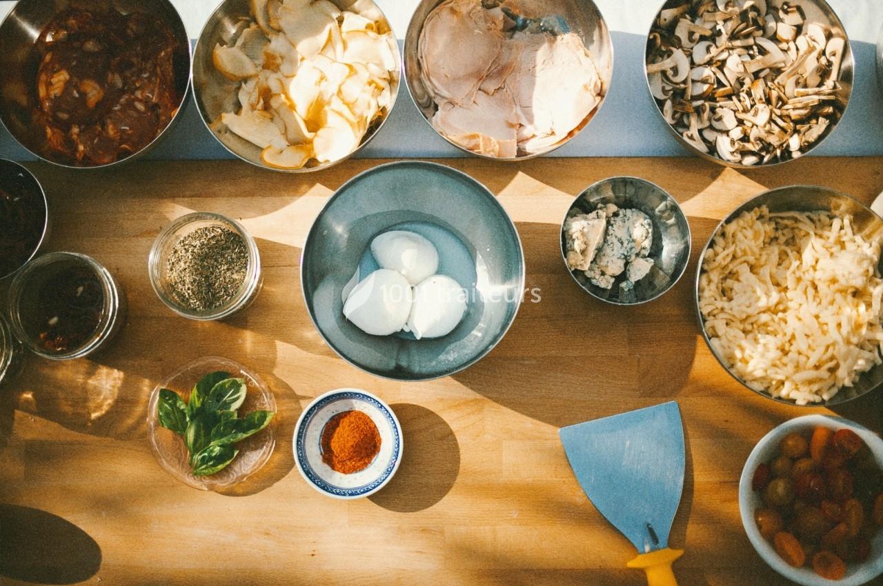 Ingrédients variés disposés sur une table en bois, comprenant œufs, légumes, épices, herbes et fromages.