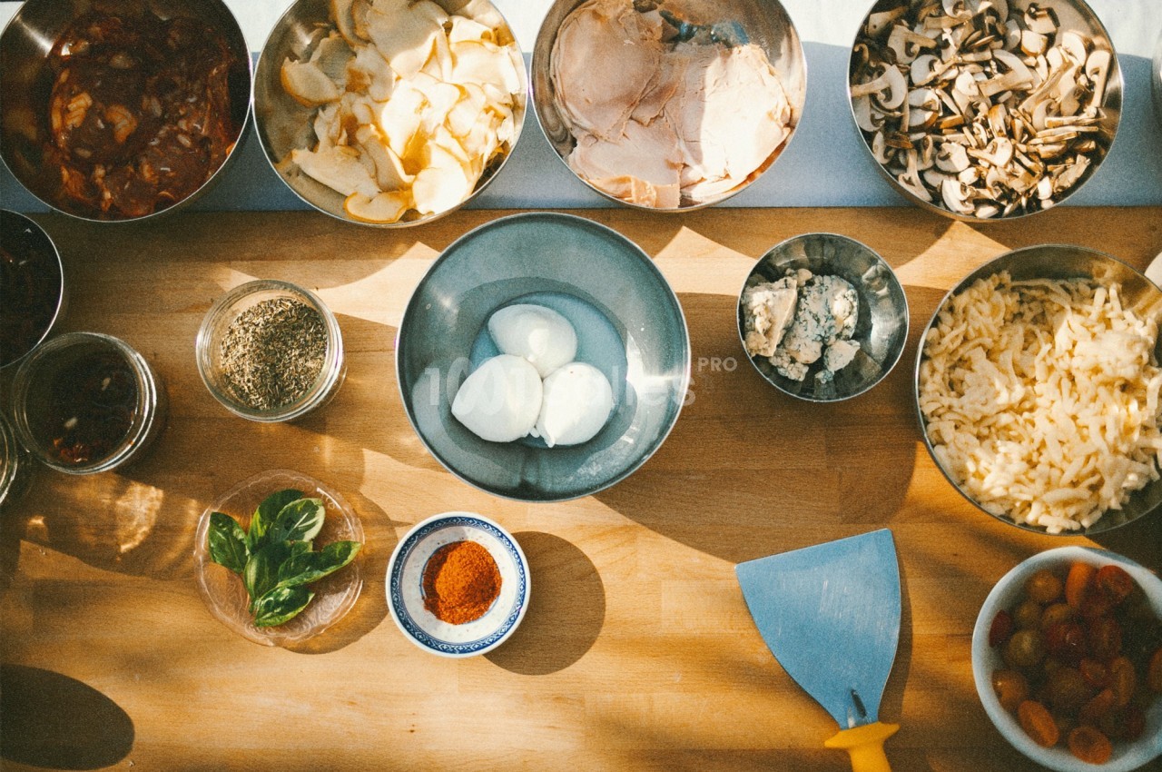 Ingrédients variés disposés sur une table en bois, comprenant œufs, légumes, épices, herbes et fromages.